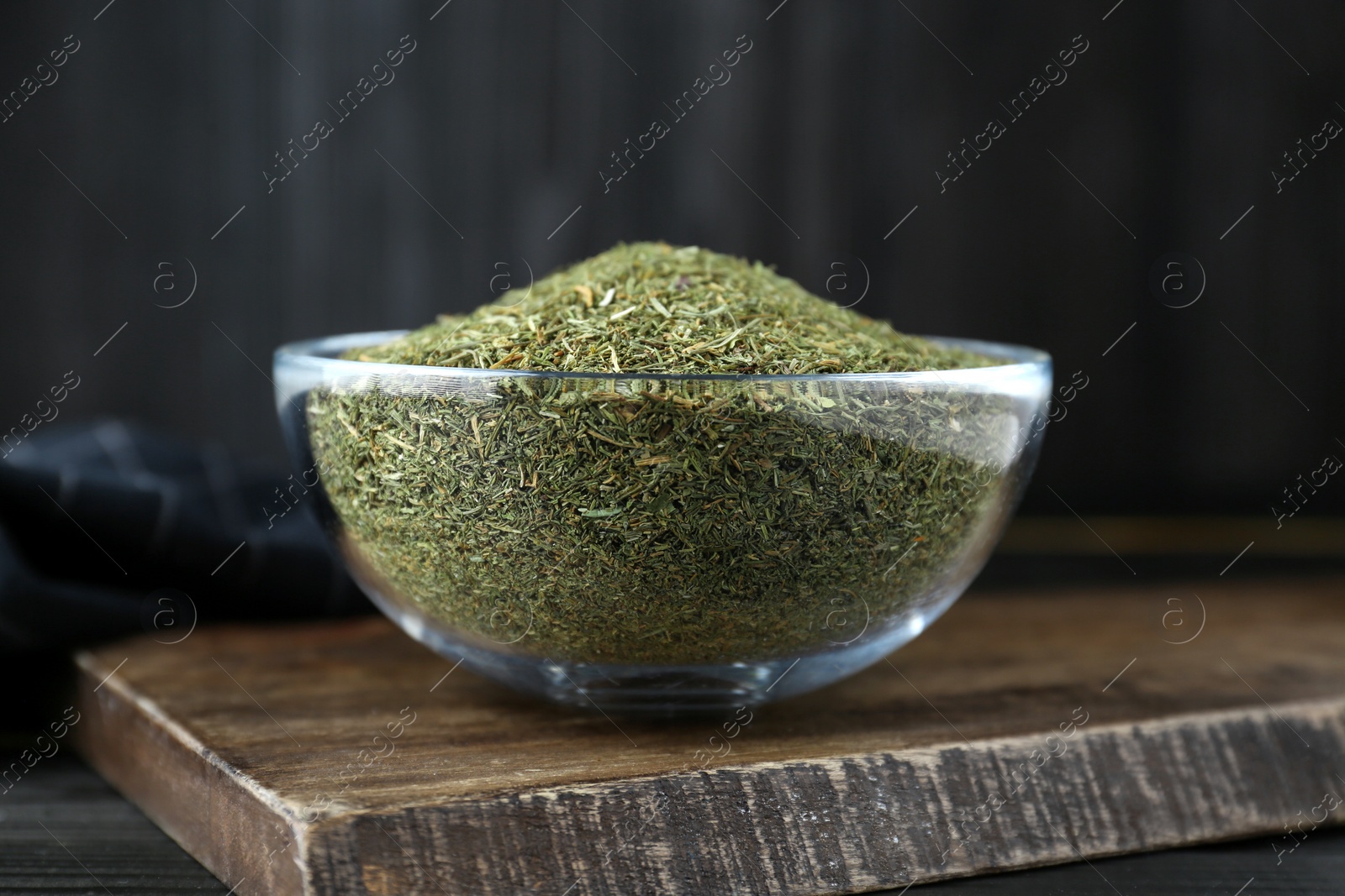 Photo of Glass bowl with dried dill on wooden table