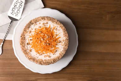 Photo of Sweet carrot cake with delicious cream on wooden table, top view. Space for text