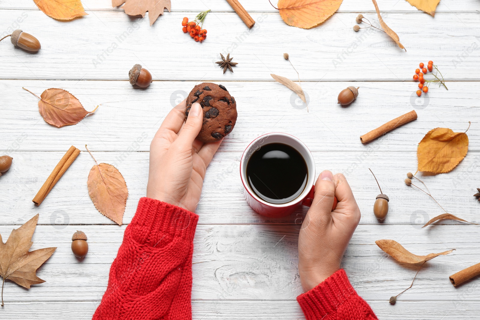 Photo of Woman with cup of hot drink at white wooden table, top view. Cozy autumn atmosphere