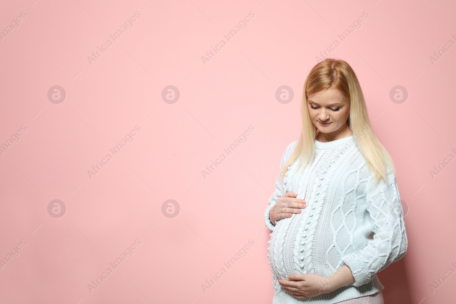 Photo of Beautiful pregnant woman in sweater on color background. Space for text