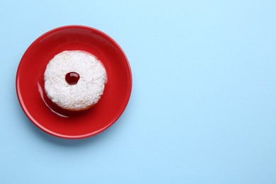 Hanukkah donut with jelly and powdered sugar on light blue background, top view. Space for text