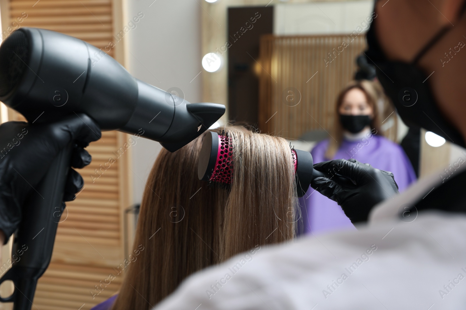 Photo of Professional stylist working with client in beauty salon, closeup. Hairdressing services during Coronavirus quarantine