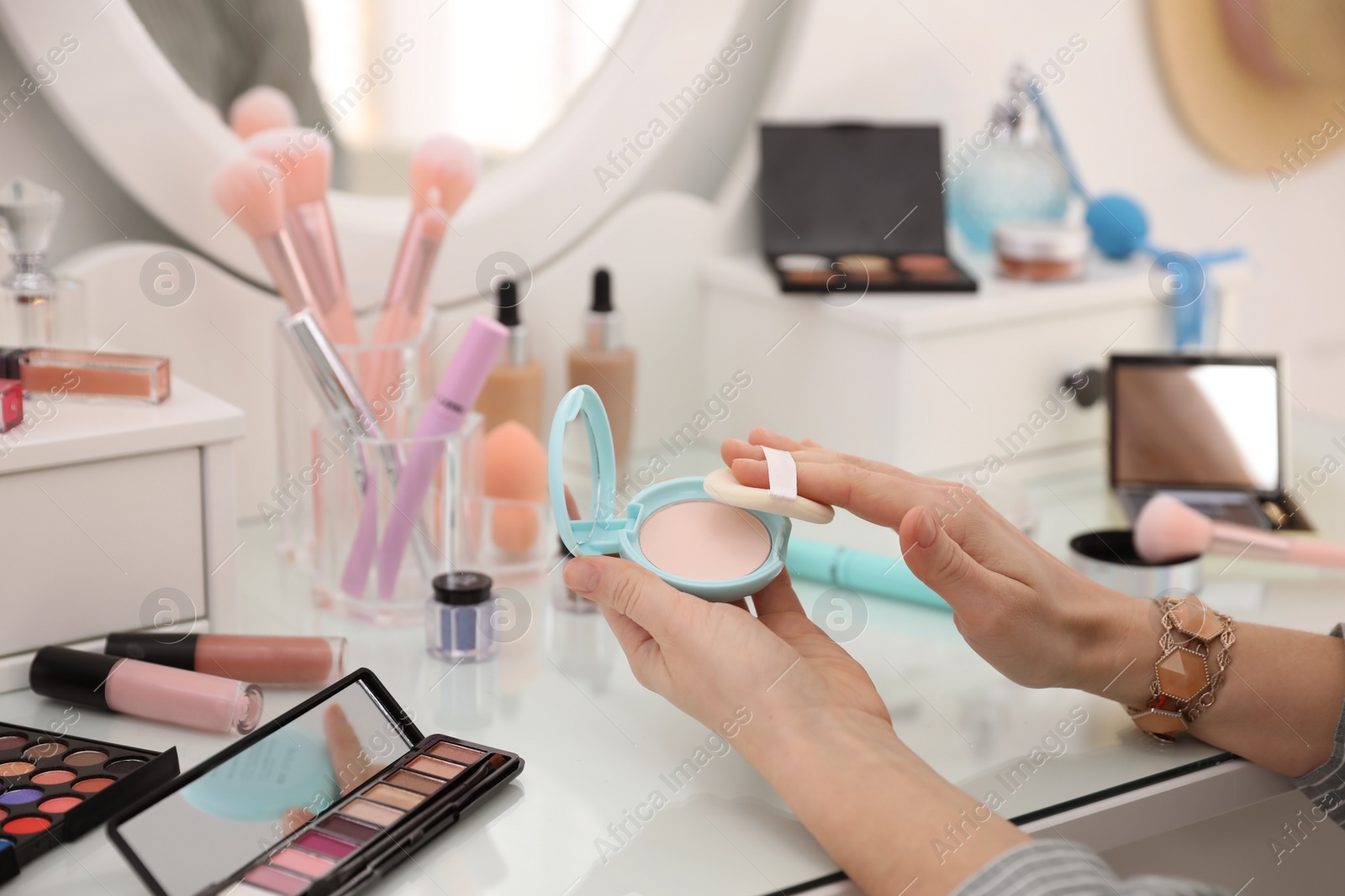 Photo of Woman applying makeup at dressing table, closeup