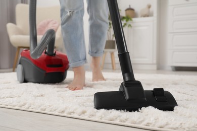 Photo of Woman cleaning carpet with vacuum cleaner at home, closeup