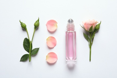 Photo of Composition with rose essential oil and flowers on white background, top view