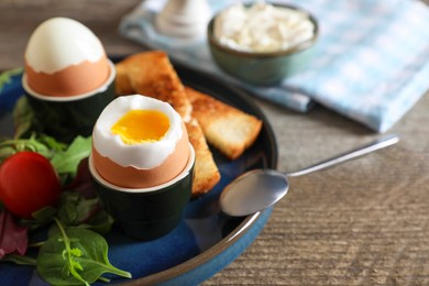 Photo of Delicious breakfast with soft boiled eggs served on wooden table, closeup