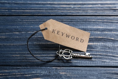 Photo of Key with tag KEYWORD on blue wooden background