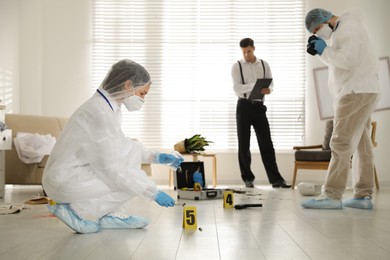 Photo of Investigators working at crime scene in messy room