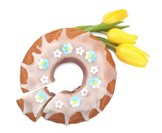 Festively decorated Easter cake and yellow tulips on white background, top view