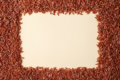Photo of Frame made with brown rice on color background, top view. Space for text