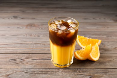 Photo of Tasty refreshing drink with coffee and orange juice on wooden table