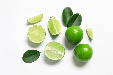 Fresh ripe limes and leaves on white background, flat lay