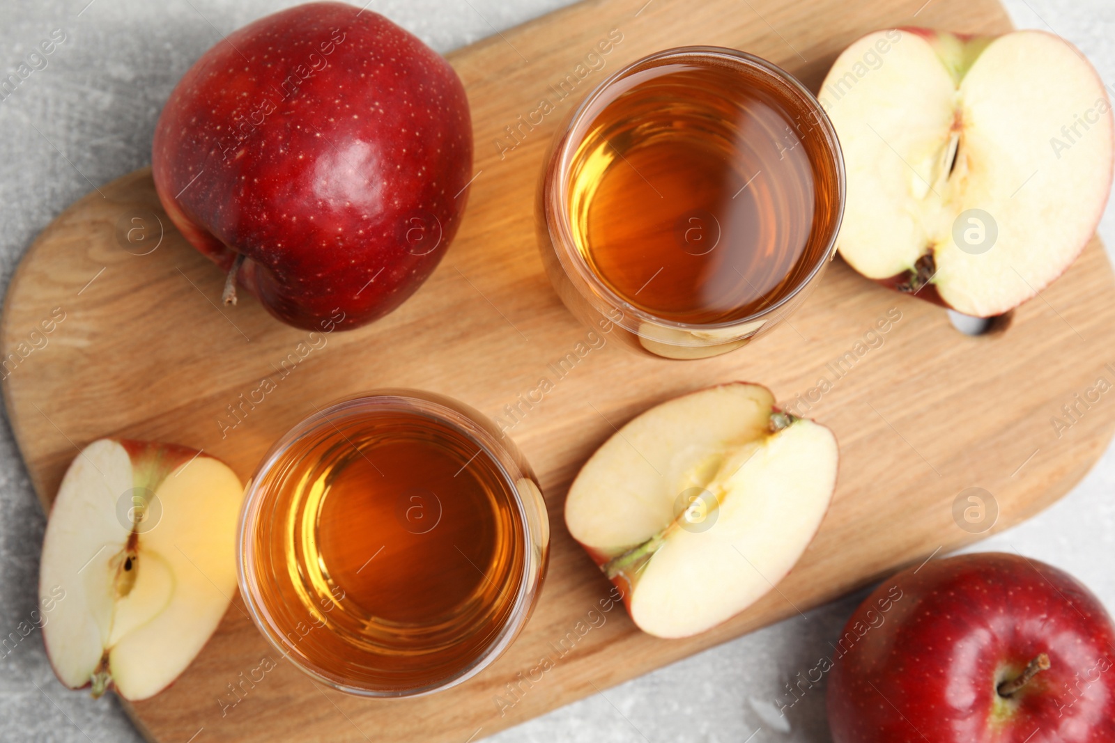 Photo of Delicious cider and ripe red apples on grey table, flat lay