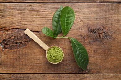 Photo of Scoop with green matcha powder on wooden table, flat lay