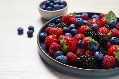 Photo of Different fresh ripe berries on light wooden table, closeup. Space for text