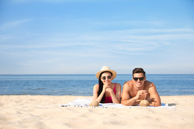 Photo of Happy couple with cocktails on sunny beach at resort. Space for text