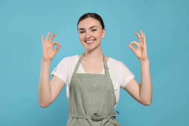 Photo of Beautiful young woman in clean apron with pattern on light blue background