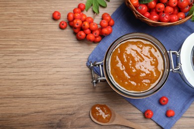 Photo of Flat lay composition with delicious rowan jam and berries on wooden table. Space for text