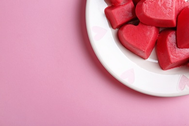 Photo of Plate with heart shaped berry ice cubes on color background, top view. Space for text