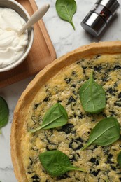 Photo of Delicious homemade spinach pie served on white marble table, flat lay