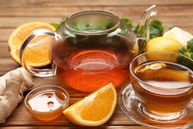 Photo of Hot tea, honey, ginger and citruses on wooden table