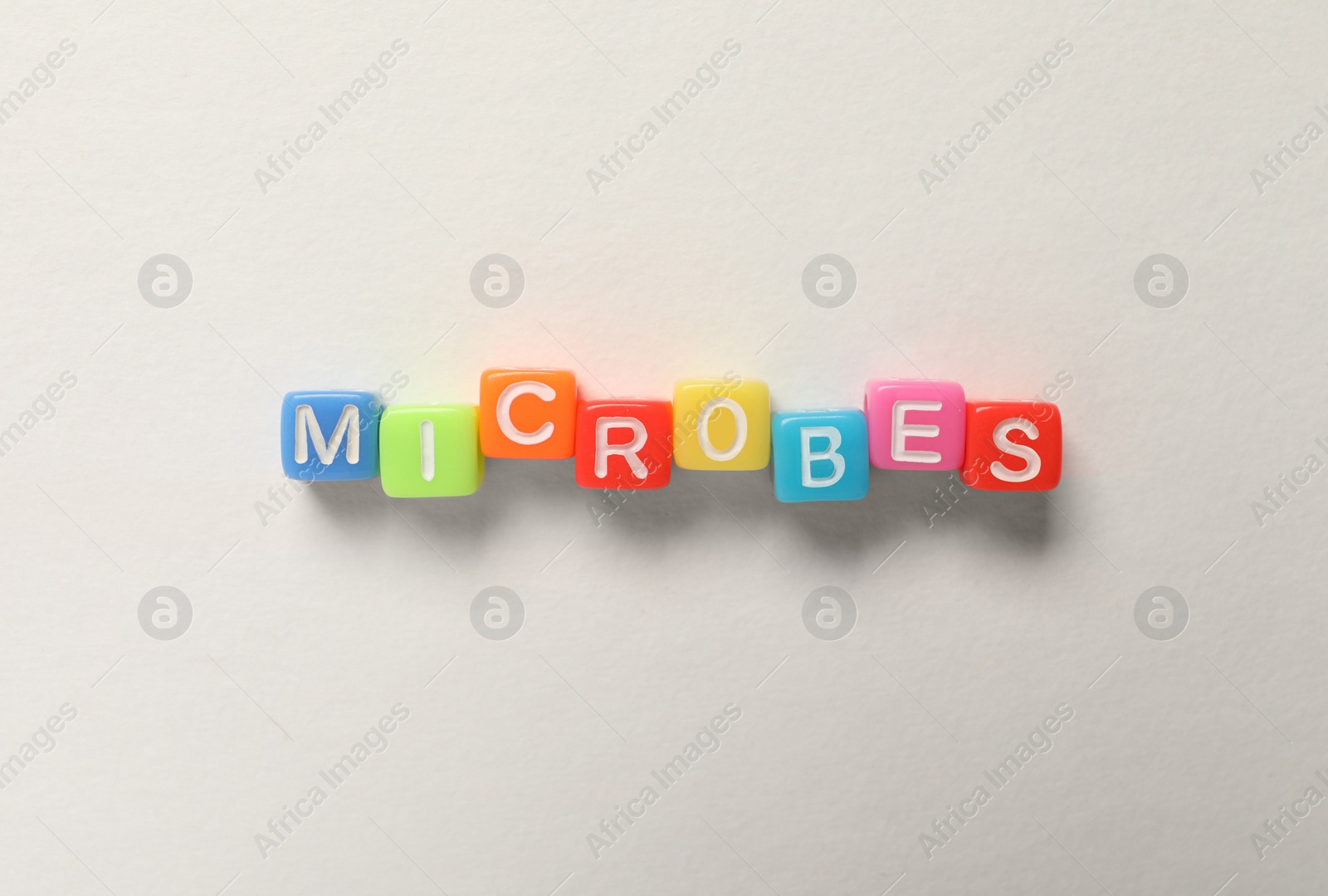 Photo of Word Microbes made with colorful cubes on white background, flat lay