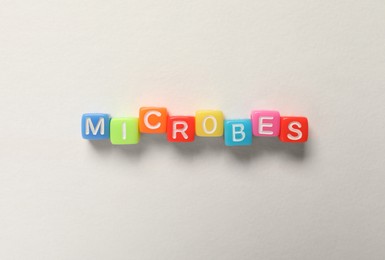 Photo of Word Microbes made with colorful cubes on white background, flat lay