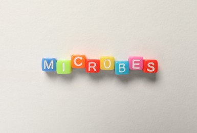 Word Microbes made with colorful cubes on white background, flat lay