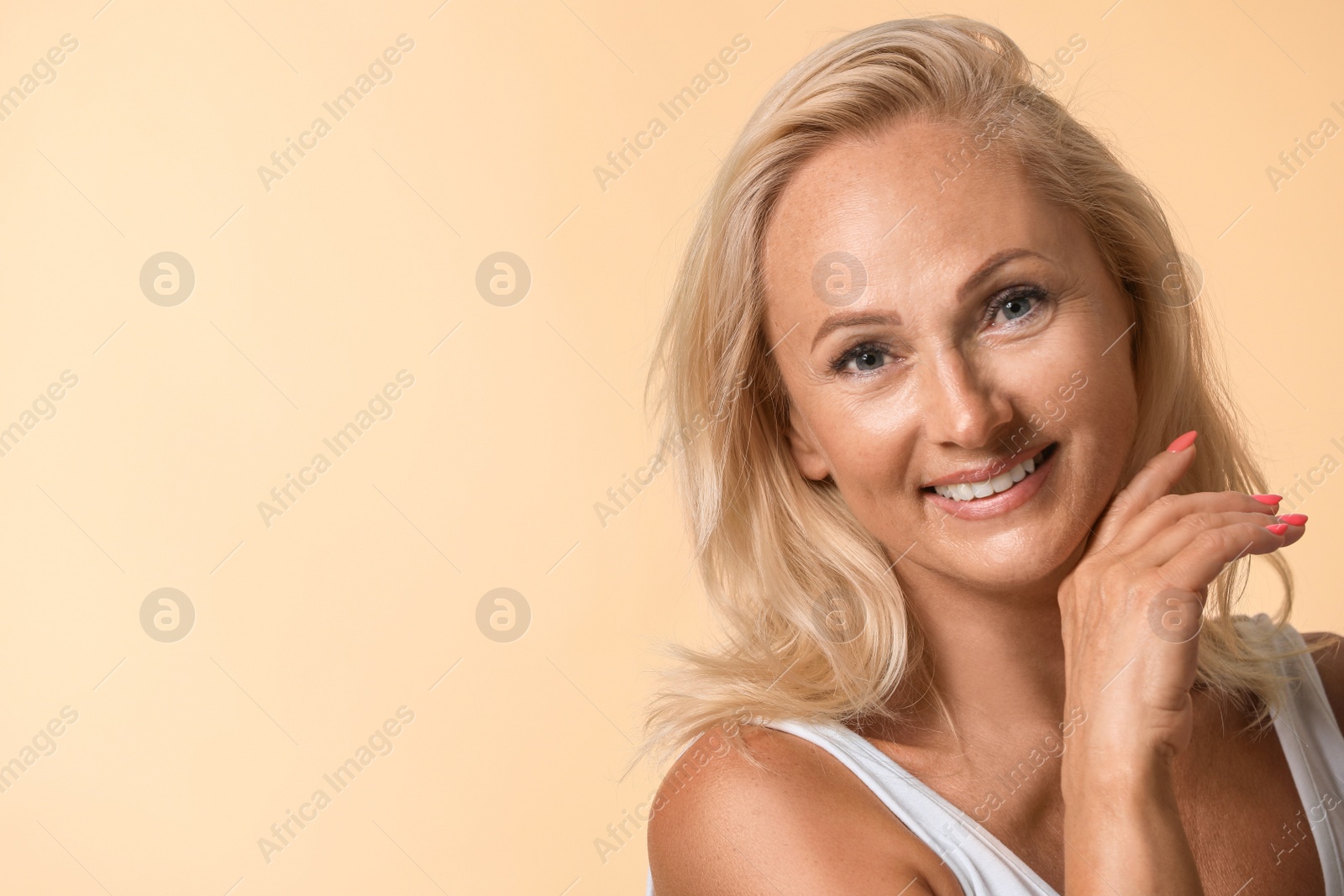 Photo of Portrait of beautiful mature woman with perfect skin on beige background. Space for text