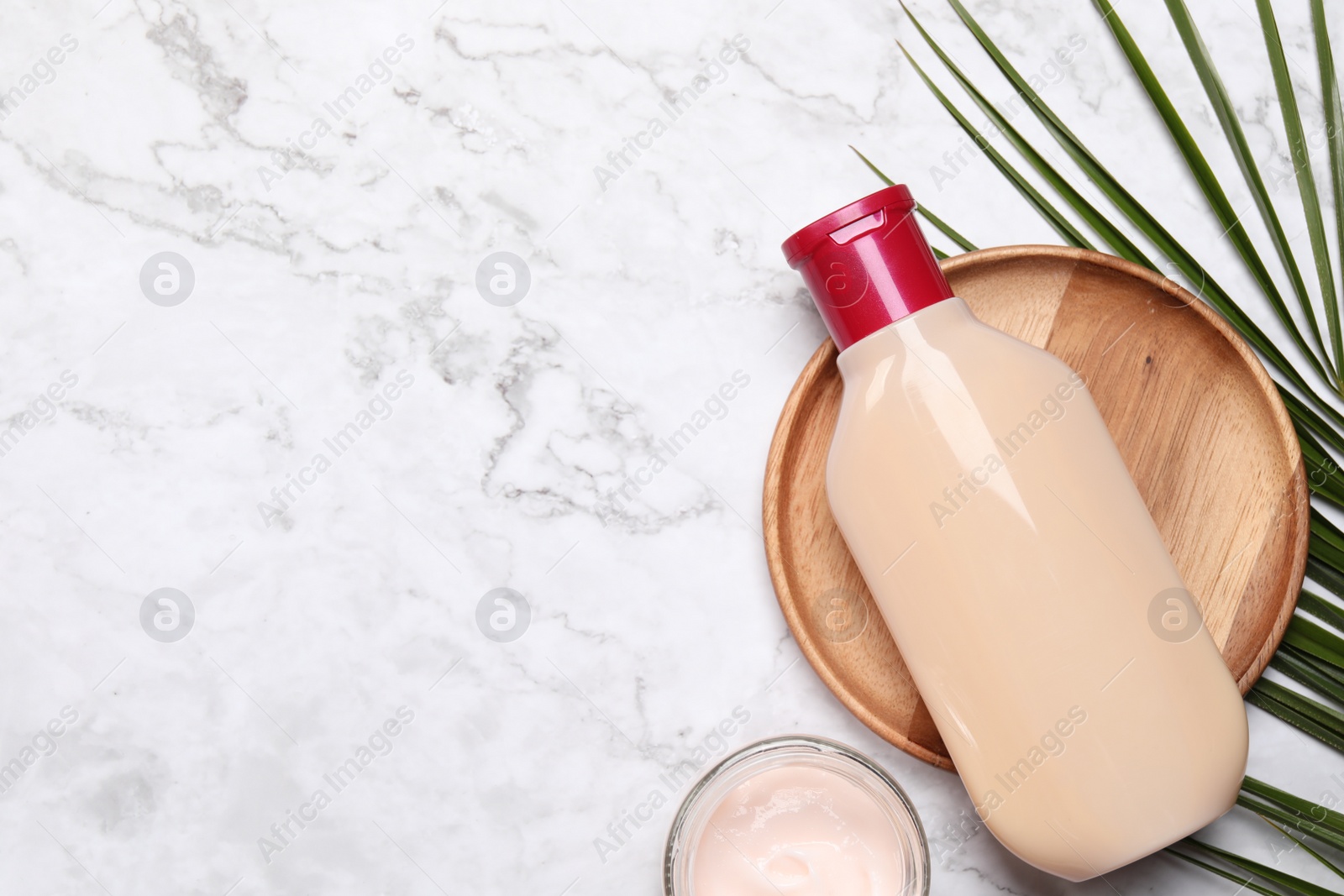 Photo of Bottle of shampoo and cream on white marble table, flat lay. Space for text