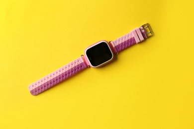 Trendy smart watch for kids on yellow background, top view