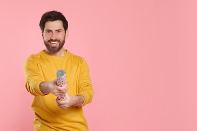 Photo of Happy man with party popper on pink background. Space for text