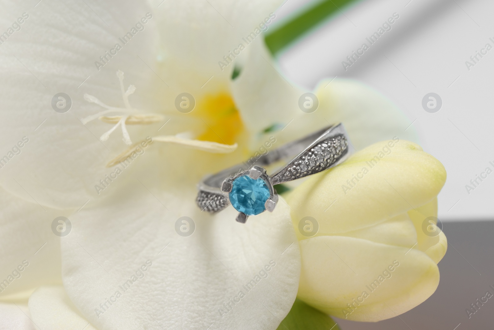 Photo of Beautiful ring with light blue gemstone on flower, closeup. Luxury jewelry