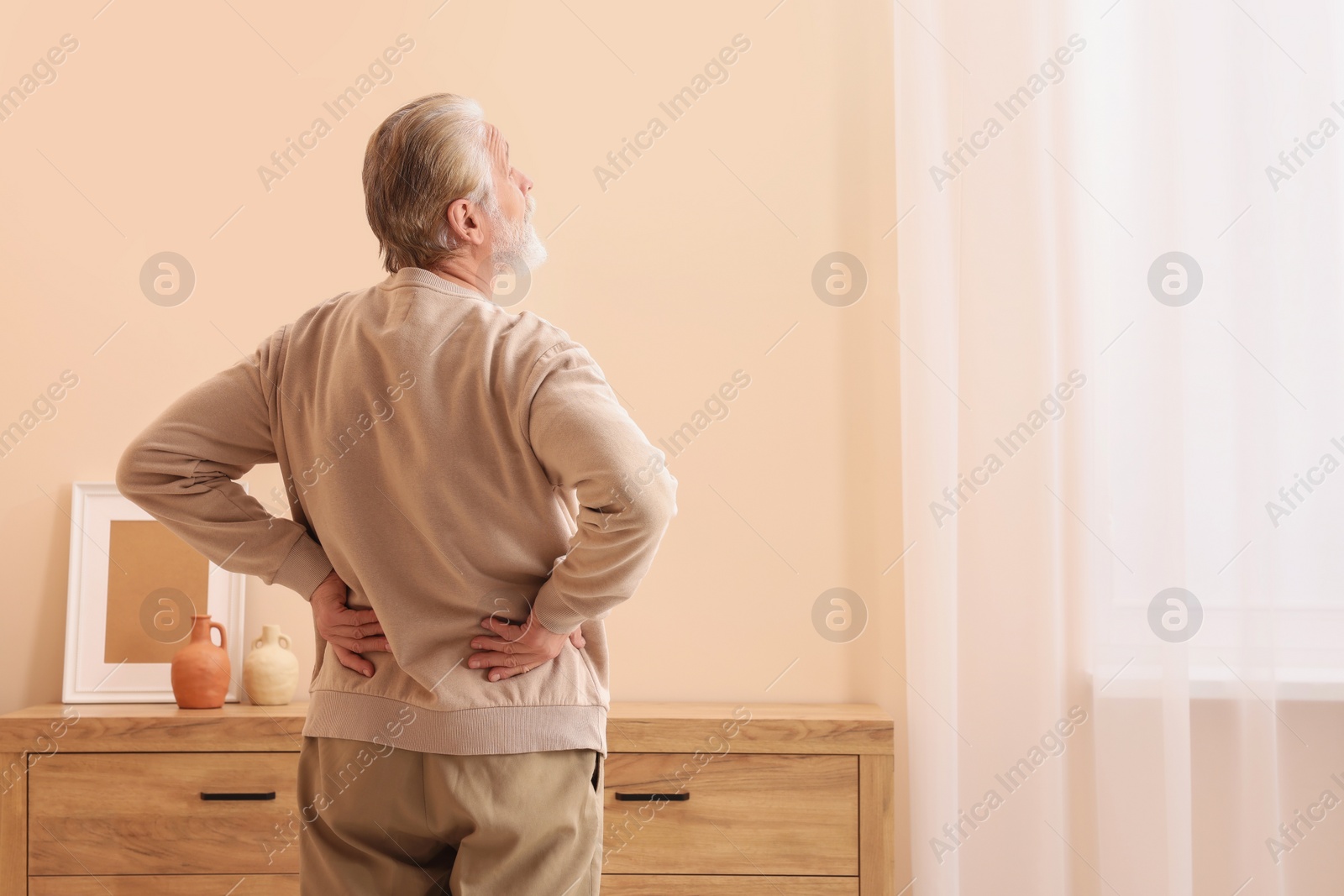 Photo of Senior man suffering from pain at home, back view with space for text. Arthritis symptoms