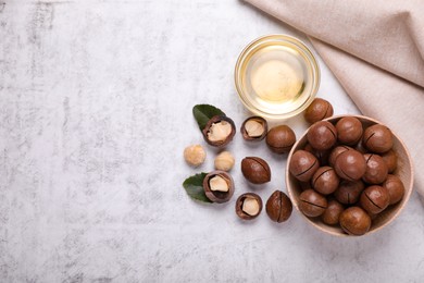 Photo of Delicious organic Macadamia nuts and natural oil on light gray table, flat lay. Space for text
