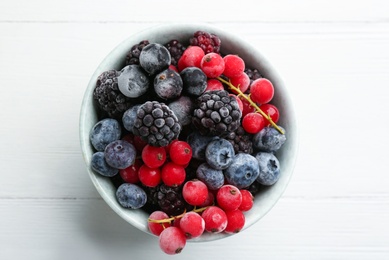 Mix of tasty frozen berries on white wooden table, top view