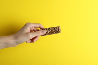 Photo of Woman holding kozinaki bar on yellow background, closeup