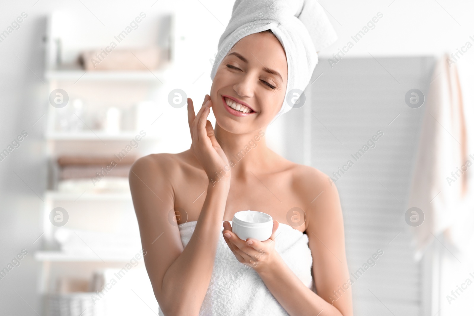 Photo of Young woman with jar of cream at home