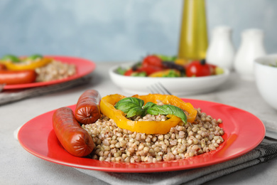 Tasty buckwheat porridge with sausages on light table. Space for text