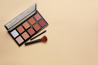 Photo of Colorful contouring palette with brushes on beige background, flat lay. Space for text