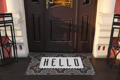 Photo of Stylish door mat with word HELLO near entrance