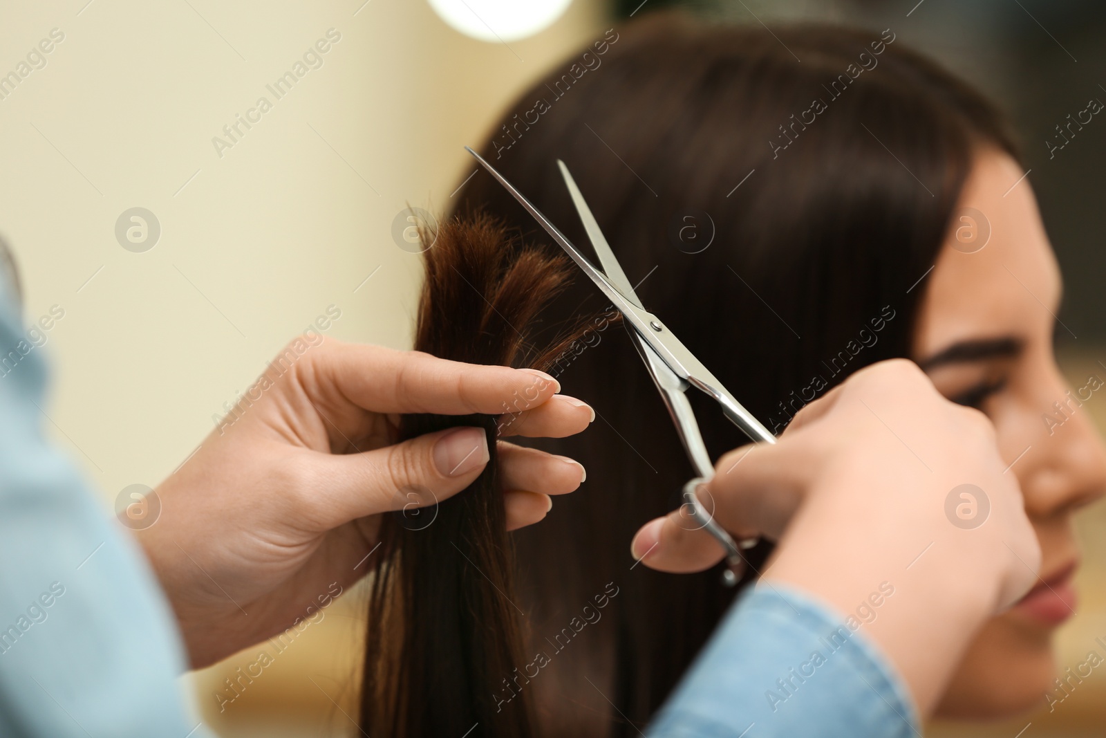 Photo of Barber making stylish haircut with professional scissors in beauty salon, closeup