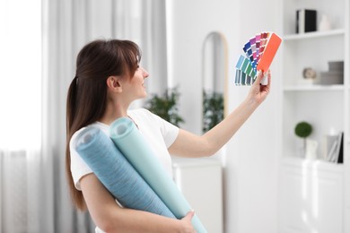 Woman with wallpaper rolls and color palette in room