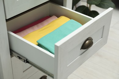 Photo of Chest of drawers with different folded clothes indoors