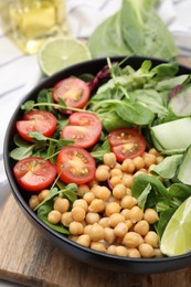 Tasty salad with chickpeas, cherry tomatoes and cucumbers on wooden board, closeup