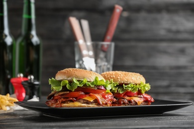 Plate with tasty burgers on wooden table