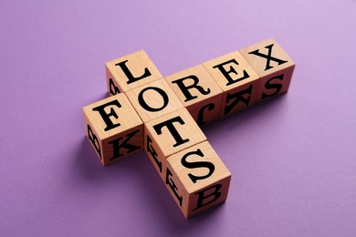 Photo of Forex lots. Wooden cubes placed as crossword on purple background, closeup
