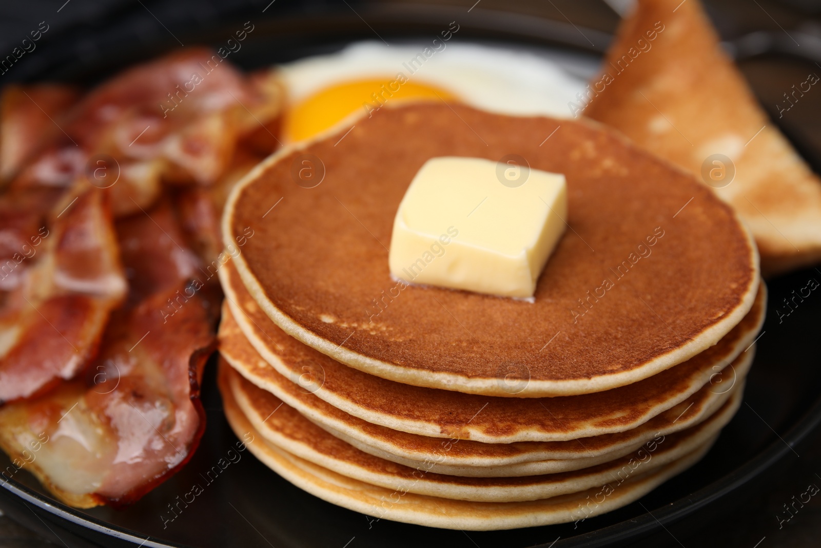 Photo of Tasty pancakes with fried egg and bacon on plate, closeup