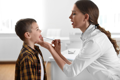 Photo of Children's doctor examining little patient's throat in clinic