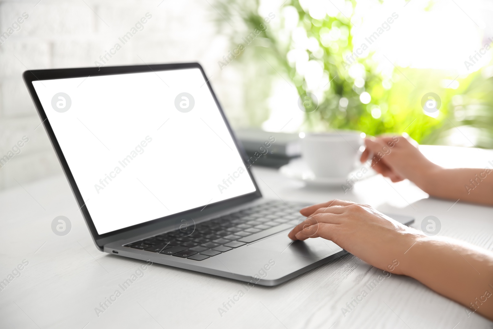 Photo of Woman working with modern laptop at white wooden table, closeup